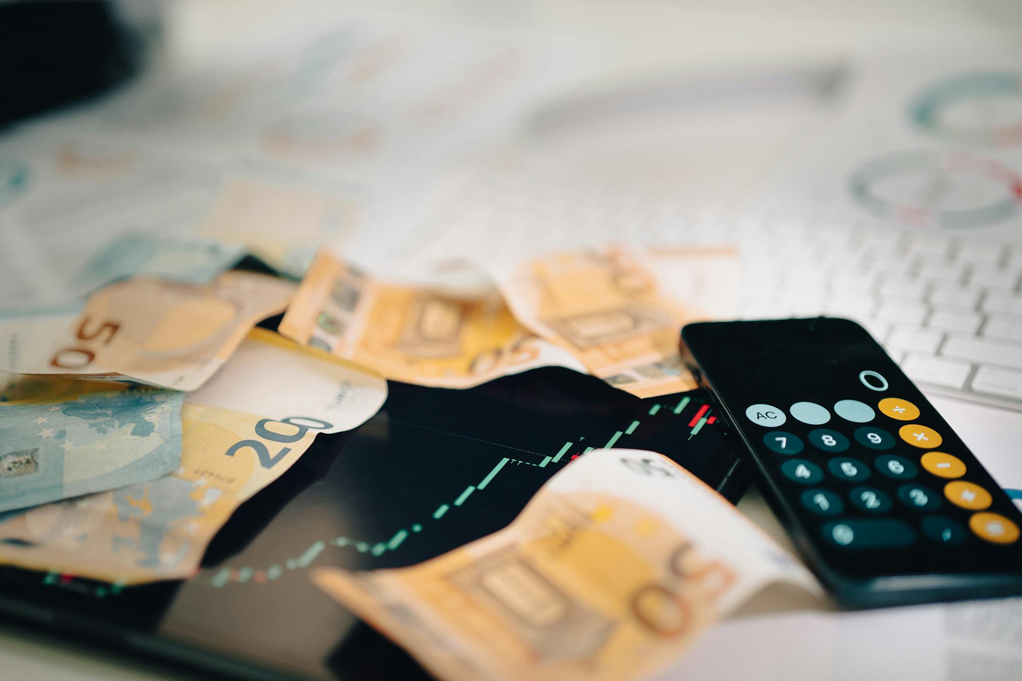 Euro banknotes scattered on a trading chart with a calculator, symbolizing finance and analysis.