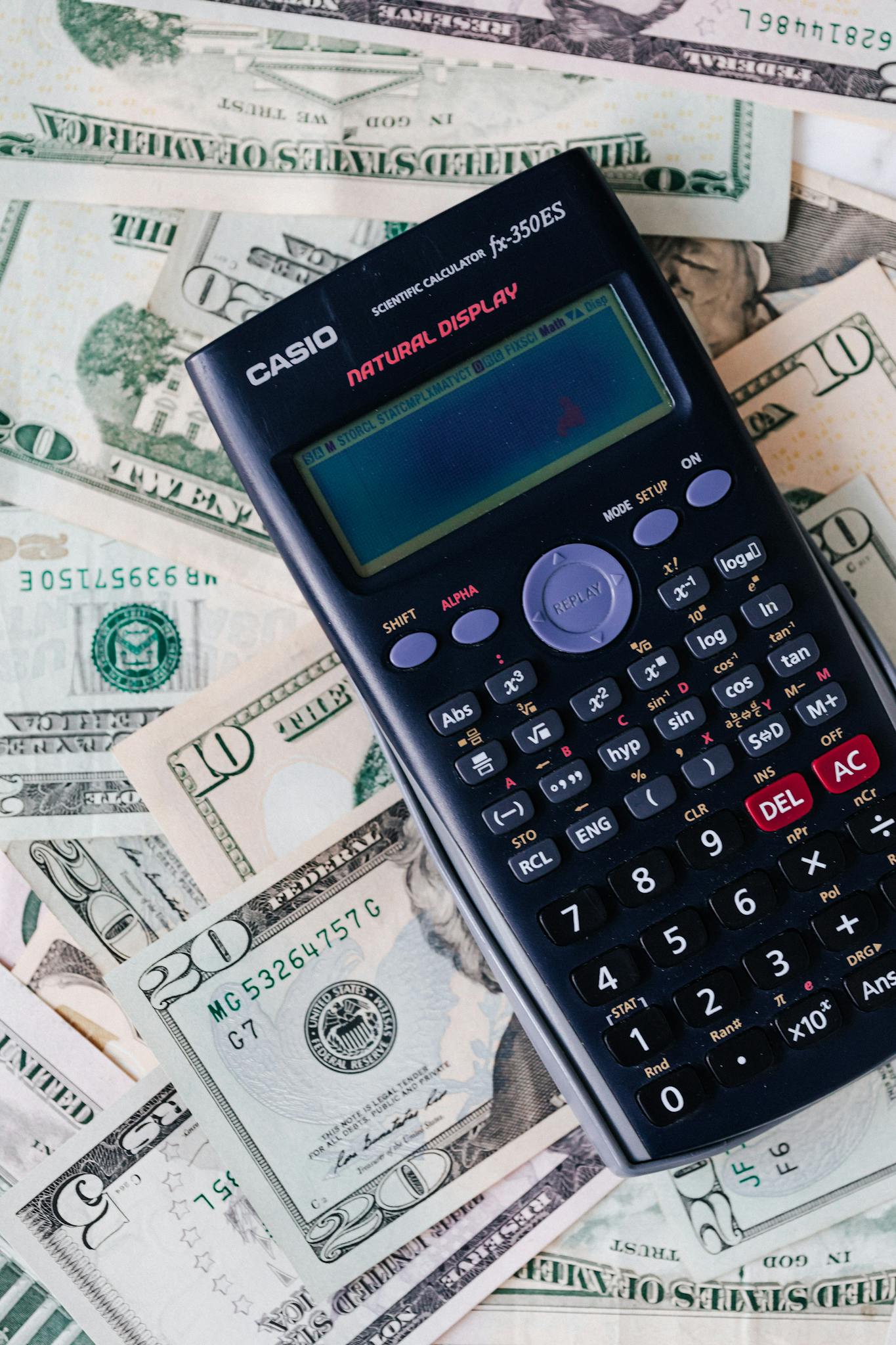 From above of electronic calculator placed over United States dollar cash money for budget planning and income and expenses calculation